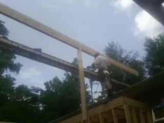 Carpenter setting a ridge beam over a new addition frame — Ice Dam Removal by Roofing Brothers in Lockhart