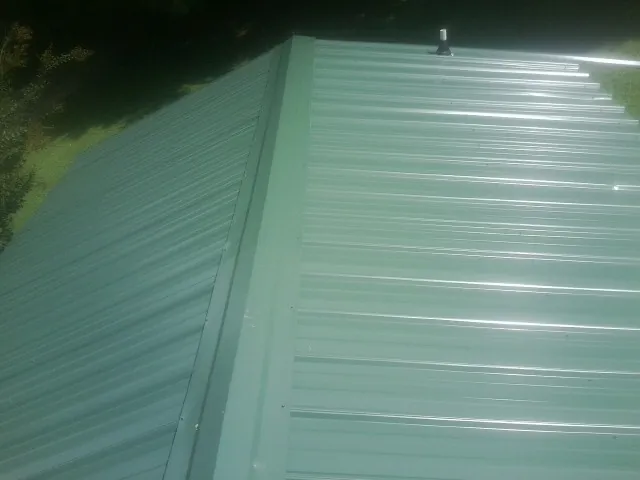 New green metal panels meeting at the ridge of a roof — Flat Roof Repair work by our crew in Lockhart