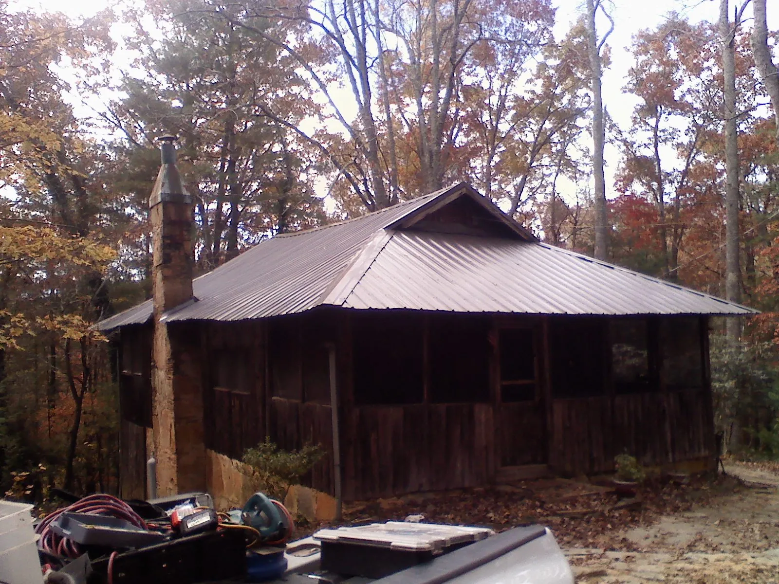 Brown metal hip roof on an old cabin with a stone chimney in Lockhart