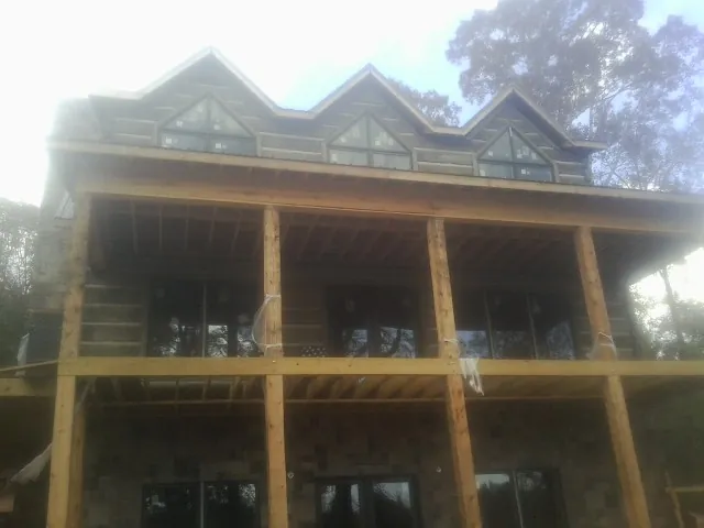 Dormers and porch framing on a large log home under construction — Roof Coating work by our crew in Lockhart