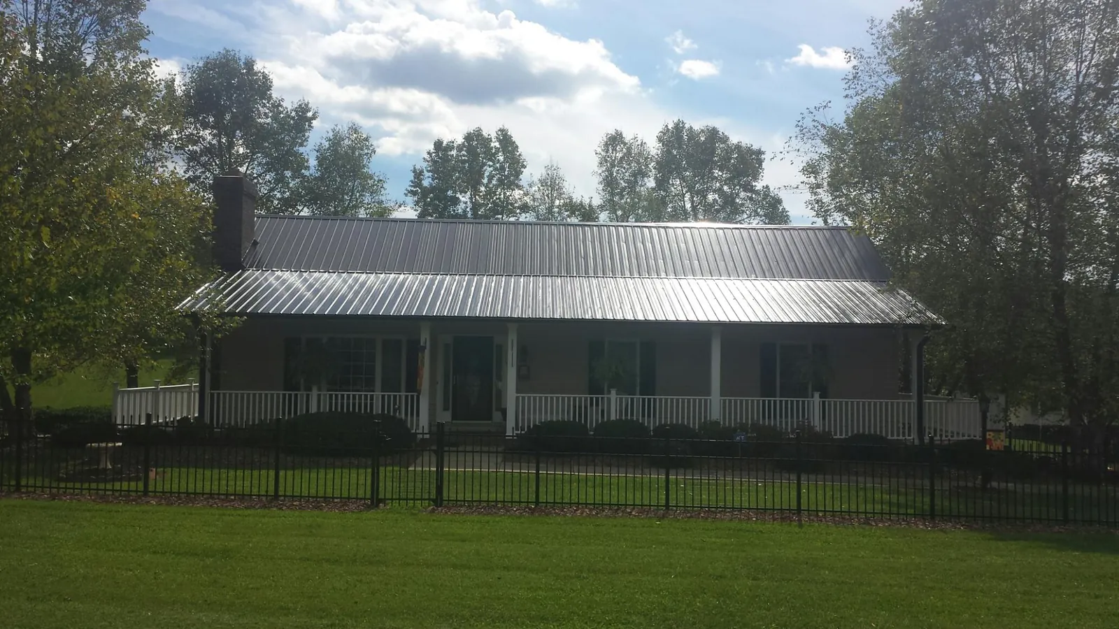 Gray metal roof on a brick ranch with a full width front porch — Gutter Guard Installation work by our crew in Lockhart
