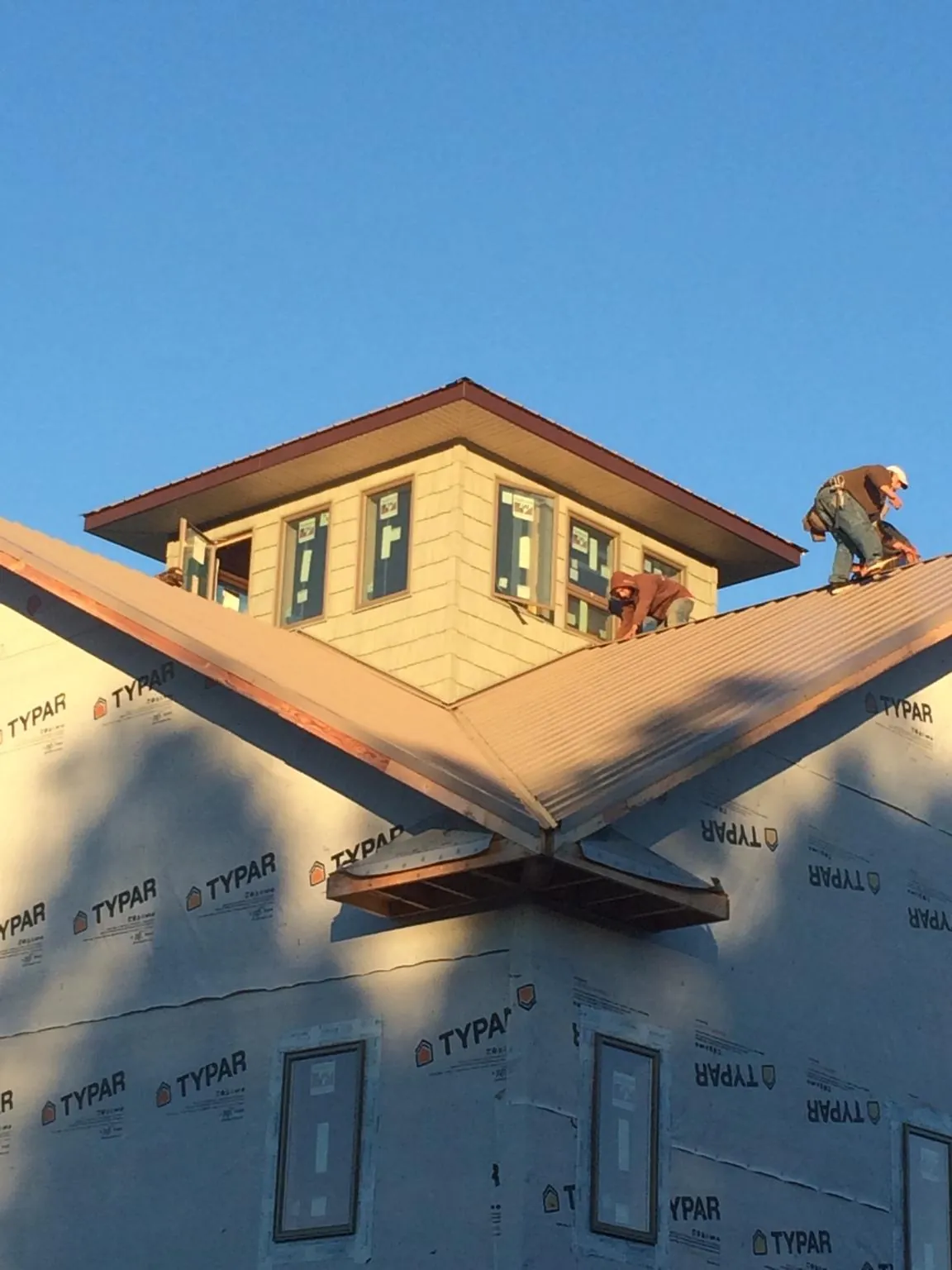 Roofers working around a rooftop cupola on a new metal roof at sunset — Roof Waterproofing in Lockhart by Roofing Brothers